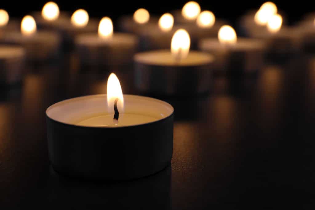 Burning candle on table in darkness