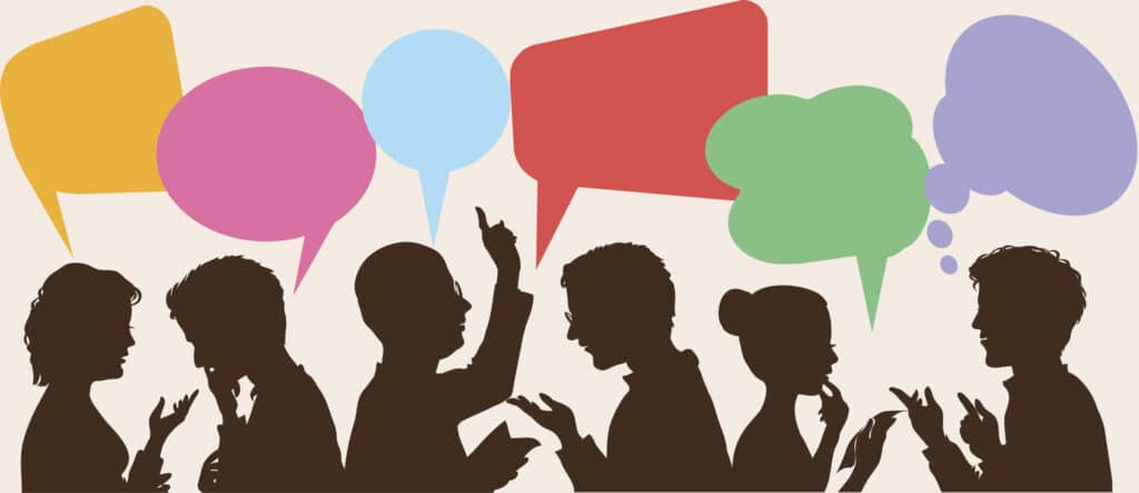 An illustration of dialogue and thoughts taking place among silhouettes of people in various positions.  The speech bubbles are yellow, pink, light blue, red and green.  The sole thought bubble is purple.  The bubbles are of varying sizes and shapes.  For example, the yellow one resembles a flag on a short flagpole, while the blue one resembles a round pin.  Some of the silhouetted people are touching their hands to their chins, and one is gesturing upward with his pointer finger.  Some of the silhouettes have their heads tilted slightly forward.