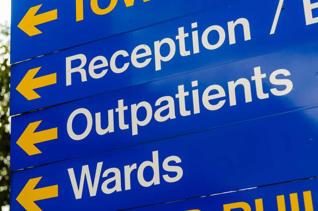 Sign in a hospital directing visitors to reception, outpatients and wards.