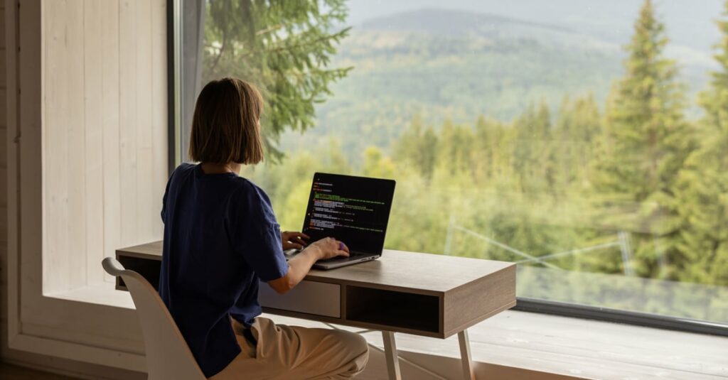 woman works on laptop remotely in house on nature