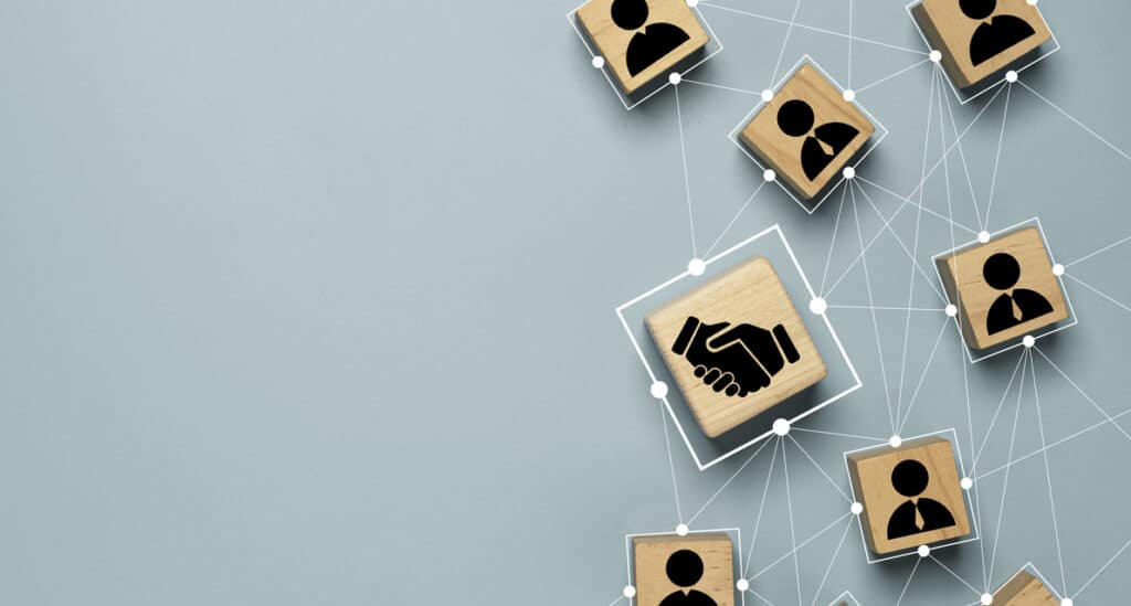 top view design on blue background of hand shaking which print screen on wooden cube block which connection with human icon for business deal and agreement concept.