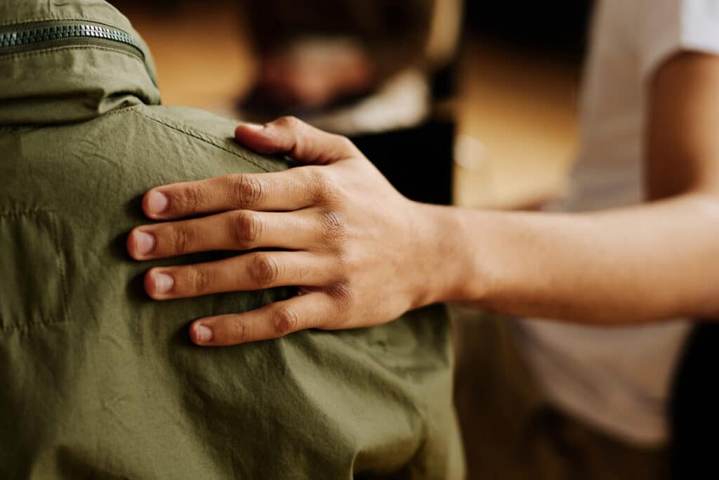 hand of young supportive man consoling his friend with post traumatic syndrome
