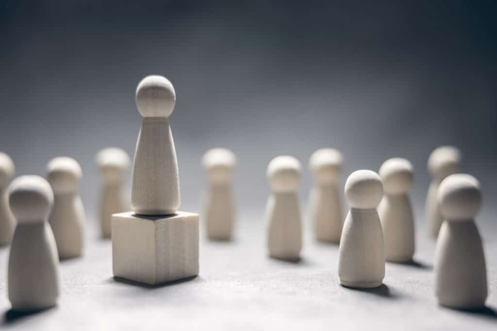 leadership wooden business team with one person standing out from the crowd on podium