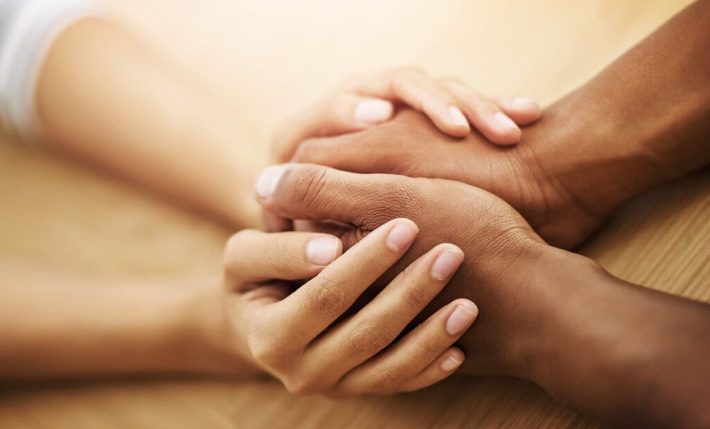 empathy, hands and support with friends in home at wooden table together for love or trust. anxiety, depression and mental health with people in apartment from above for community, hope or psychology